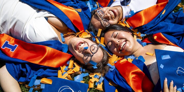 Students in convocation regalia laying in confetti.